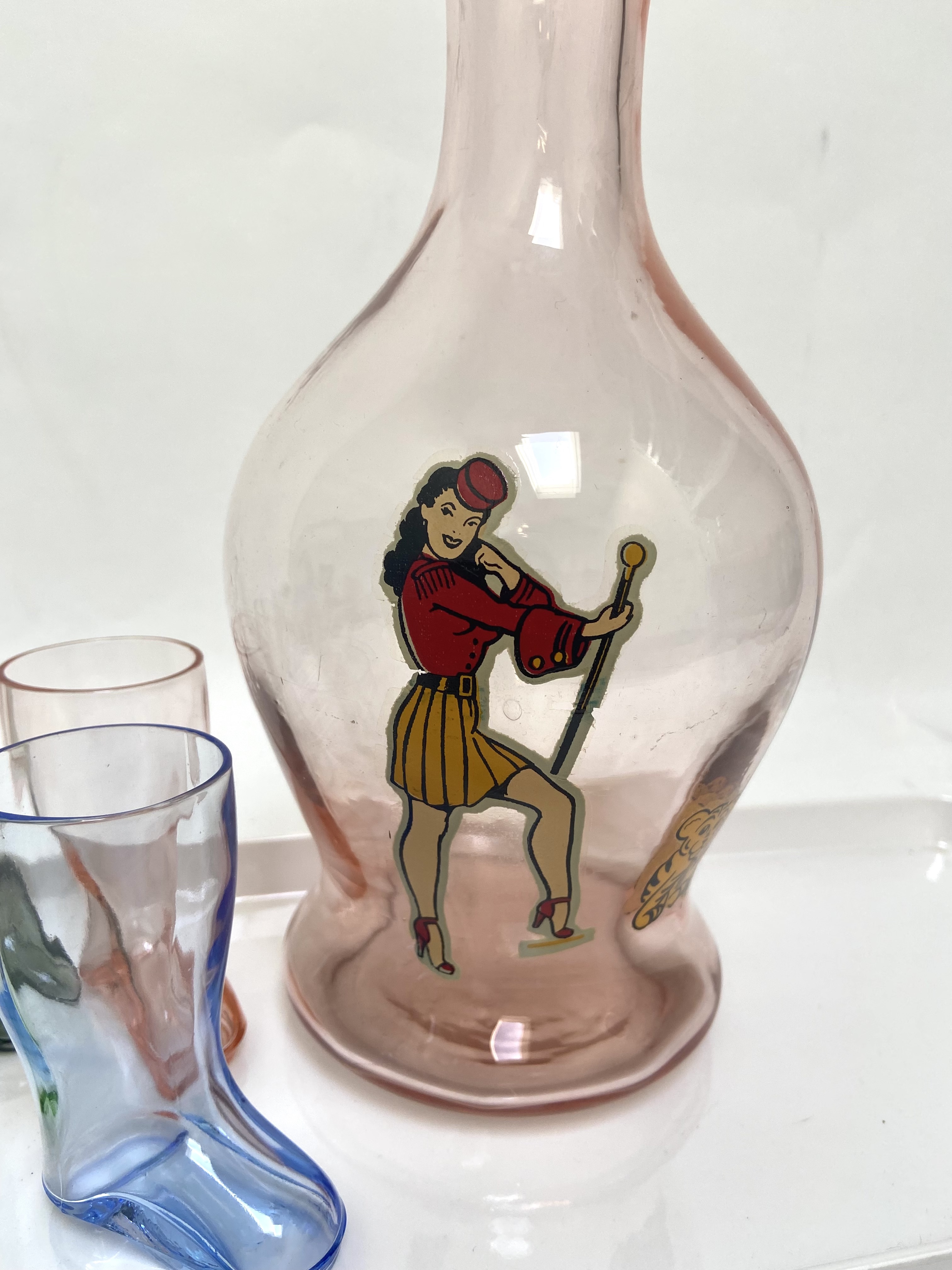 Barsetje uit de jaren vijftig met pin-up fles en shotglaasjes in laars vorm