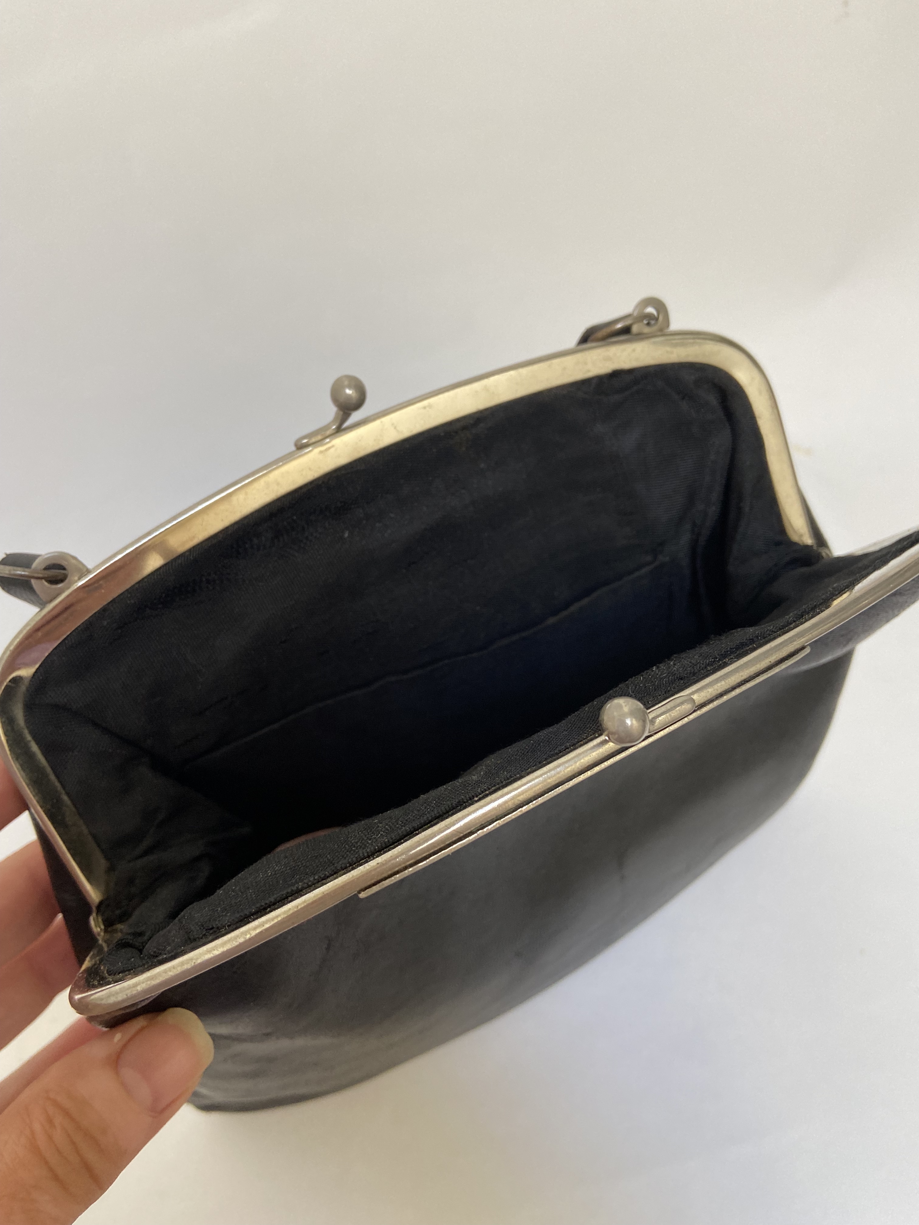 Zwart leren handtasje met een versierde kisslock sluiting